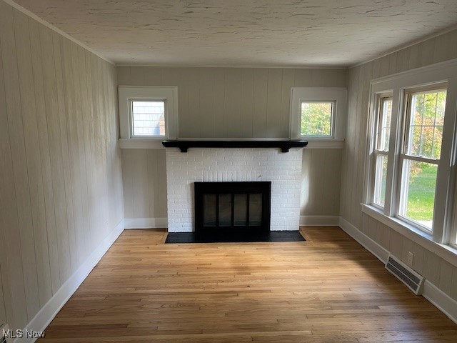 1356 Plainfield Road Cleveland, OH 44121 - Photo 6 of 12 Unfurnished living room with a brick fireplace, light wood-style floors, and wooden walls
