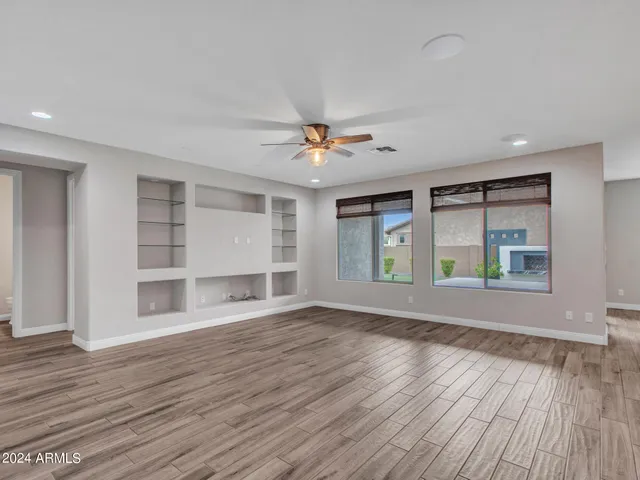 a view of an empty room with wooden floor and a kitchen