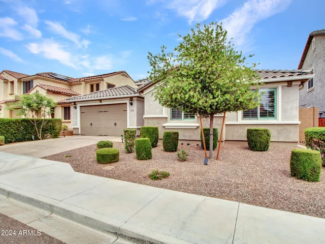 a front view of a house with garden and plants