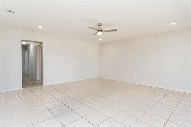an empty room with white walls and ceiling fan