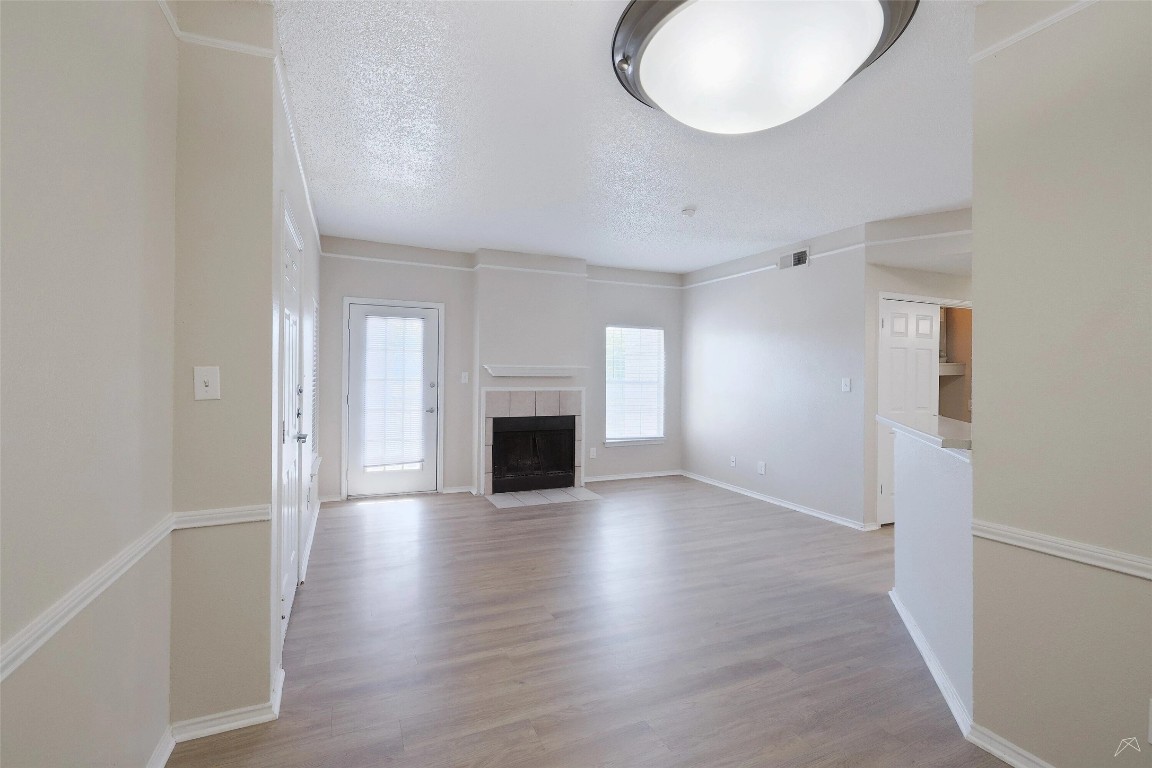 11908 Anderson Mill Road, Unit 1121 Austin, TX 78726 - Photo 12 of 24 Unfurnished living room with a fireplace, light wood-type flooring, and a textured ceiling