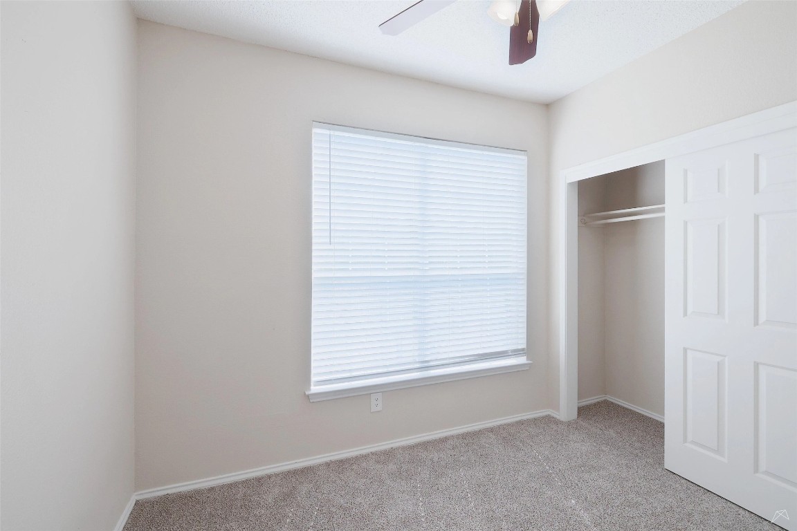 11908 Anderson Mill Road, Unit 1121 Austin, TX 78726 - Photo 18 of 24 Unfurnished bedroom featuring light colored carpet, a ceiling fan, and a closet