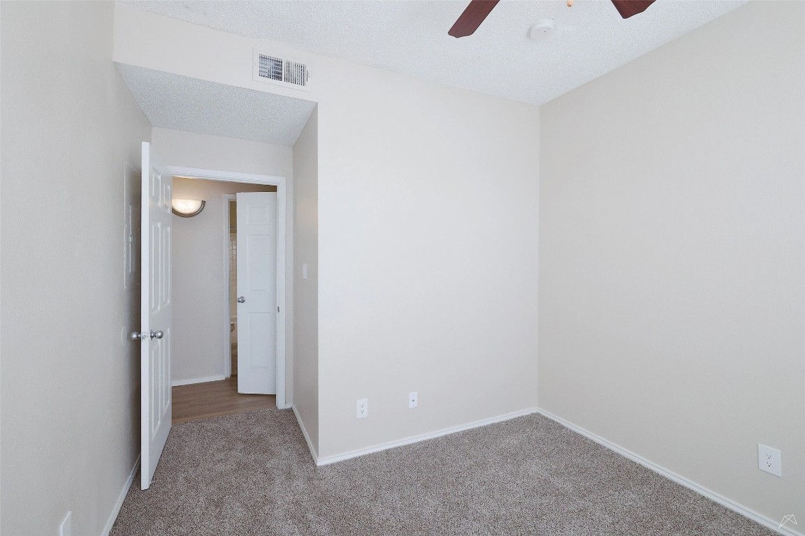 11908 Anderson Mill Road, Unit 1121 Austin, TX 78726 - Photo 19 of 24 Unfurnished room with carpet floors, a ceiling fan, and a textured ceiling
