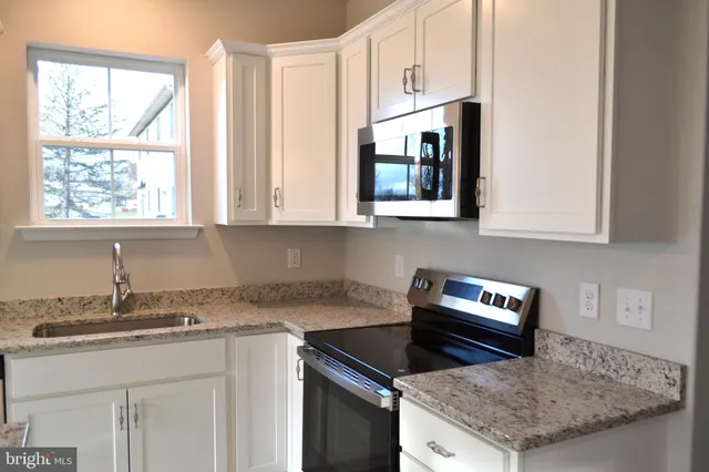 a kitchen with granite countertop a stove a sink and a microwave