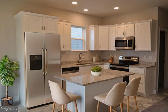 a kitchen with stainless steel appliances granite countertop a refrigerator a stove a sink a dining table and chairs with wooden floor