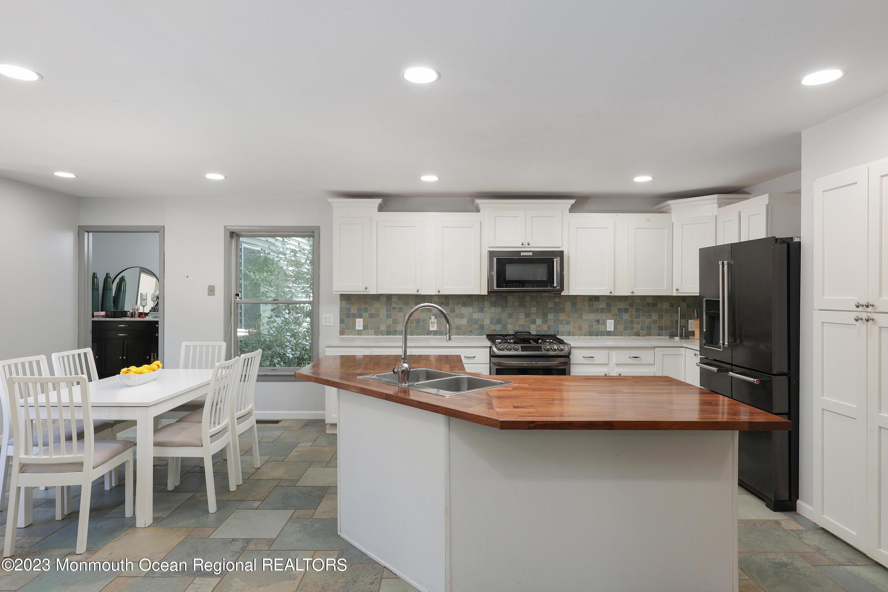 2450 Capshaw Road Forked River, NJ 08731 - Photo 16 of 37 a kitchen with stainless steel appliances granite countertop a stove a sink a refrigerator and white cabinets with wooden floor