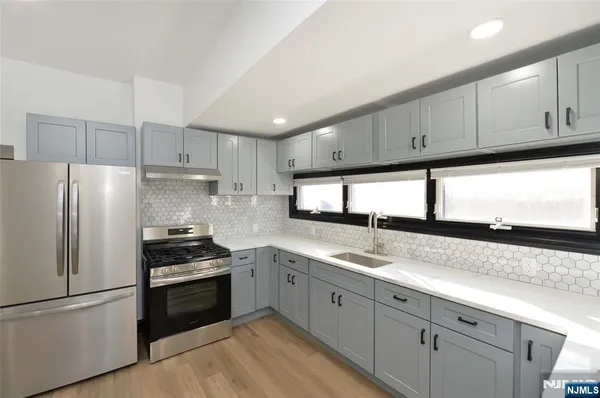 a kitchen with granite countertop white cabinets and stainless steel appliances