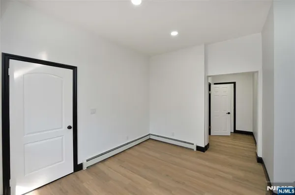 a view of an empty room with wooden floor and closet