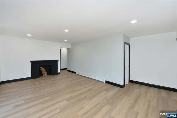 a view of an empty room with wooden floor and a fireplace