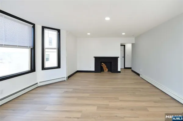 a view of an empty room with a window and fireplace