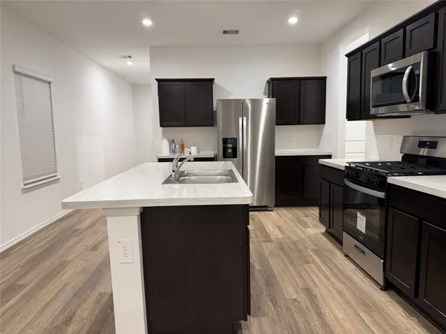 a kitchen with a sink a microwave a refrigerator and cabinets