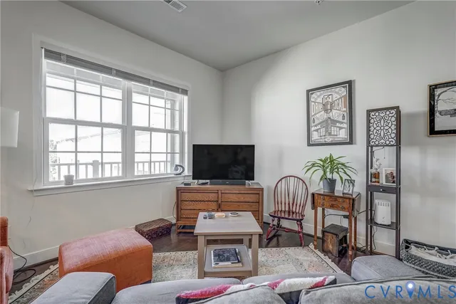 a living room with furniture a flat screen tv and a window