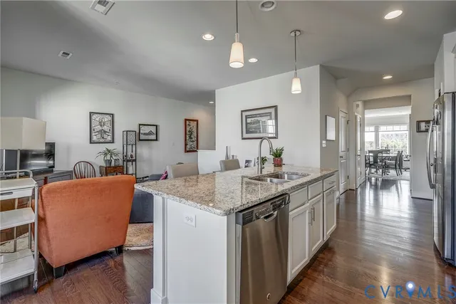 a living room with stainless steel appliances granite countertop furniture wooden floor and a kitchen view
