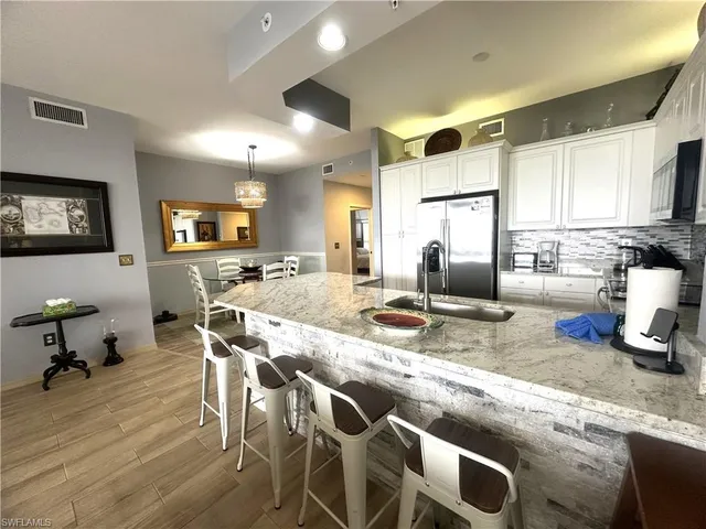 a kitchen with stainless steel appliances granite countertop a sink a stove and a wooden floors
