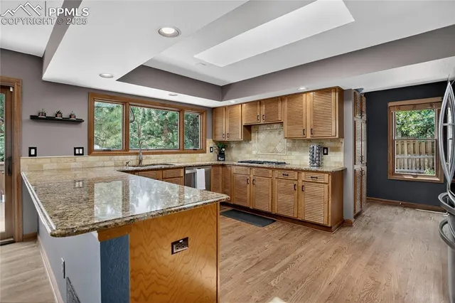 a kitchen with stainless steel appliances granite countertop a sink a stove and a wooden floors
