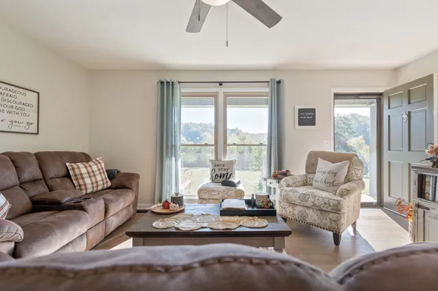 a living room with furniture large windows and a chandelier