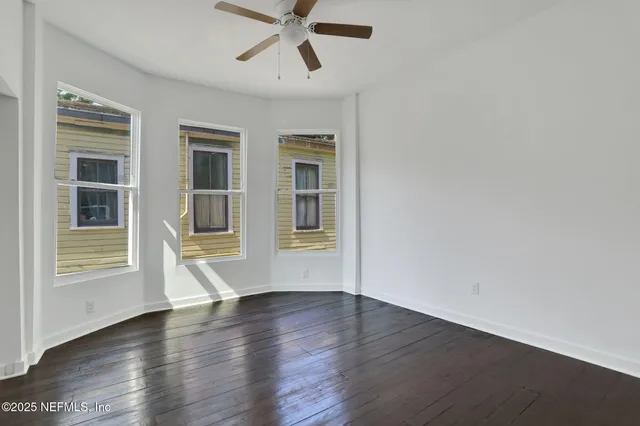 a view of empty room with wooden floor and fan