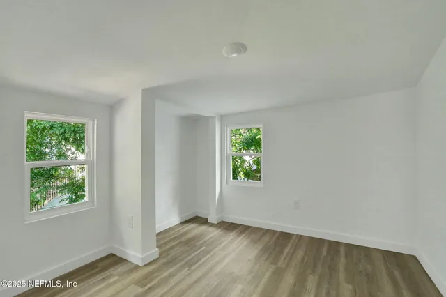 an empty room with wooden floor and windows