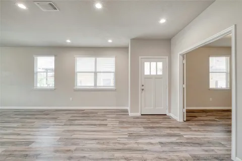 an empty room with wooden floor and windows