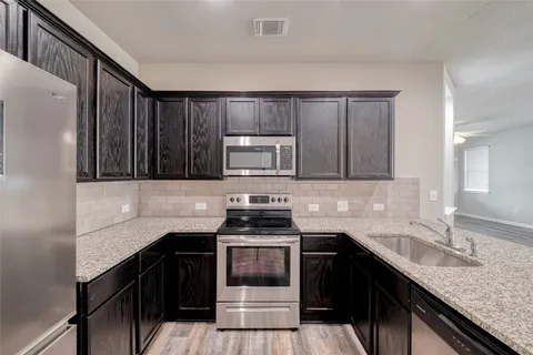a kitchen with granite countertop a stove a sink and a refrigerator