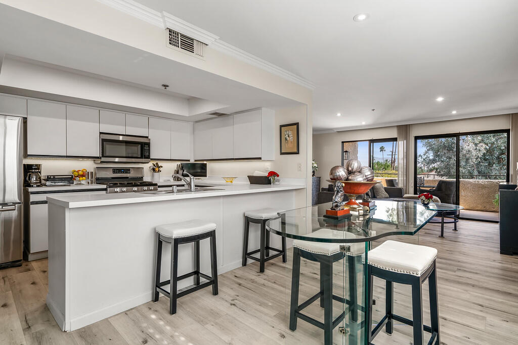 200 East Racquet Club Road, Unit 54 Palm Springs, CA 92262 - Photo 9 of 29 a kitchen with a table chairs refrigerator and cabinets
