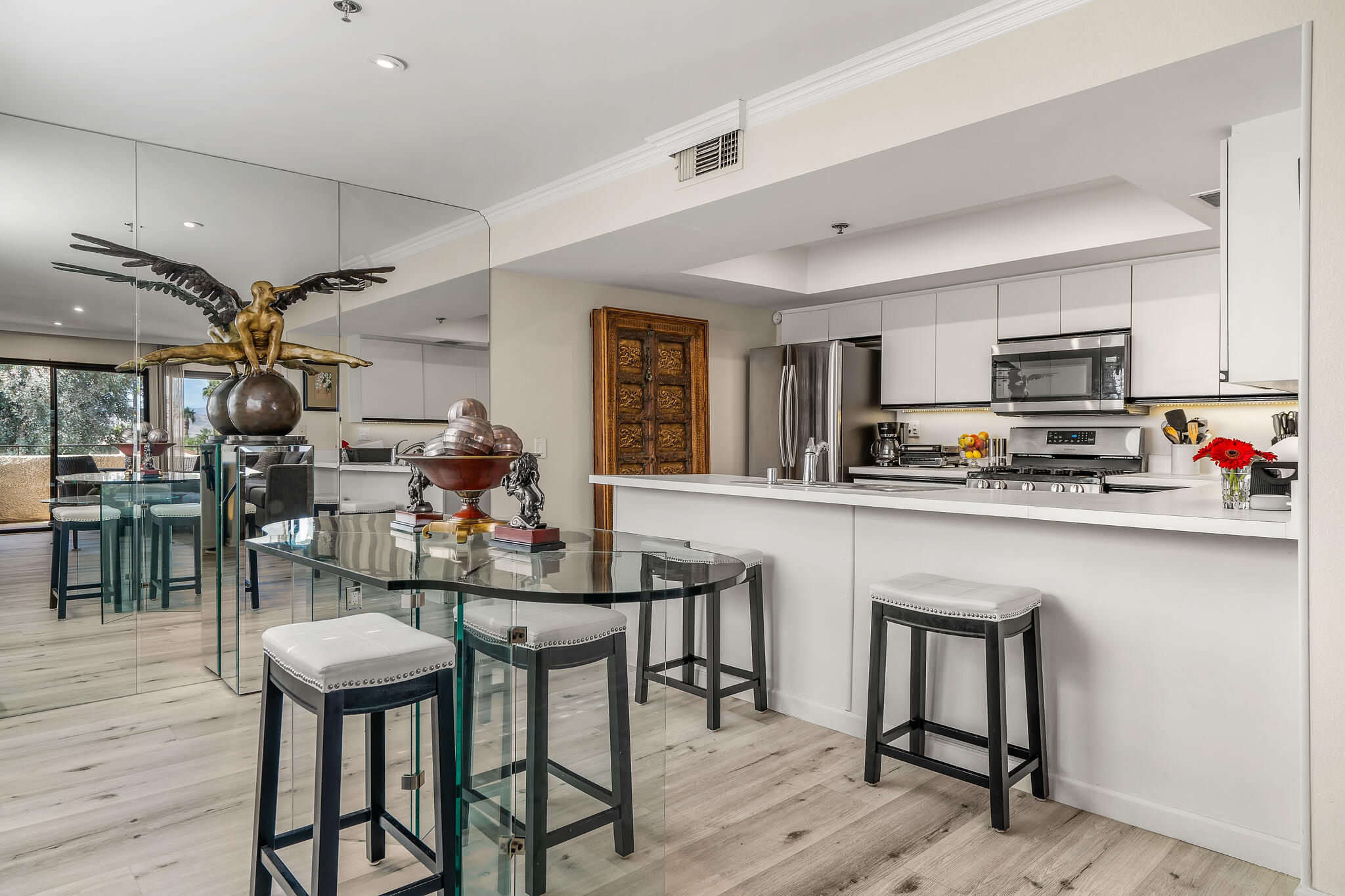 200 East Racquet Club Road, Unit 54 Palm Springs, CA 92262 - Photo 10 of 29 a kitchen with stainless steel appliances kitchen island granite countertop a table chairs sink and cabinets