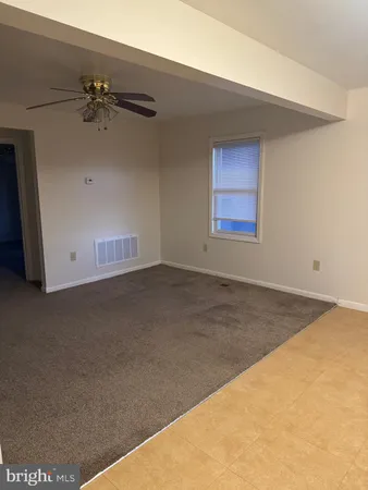 an empty room with a ceiling fan and window