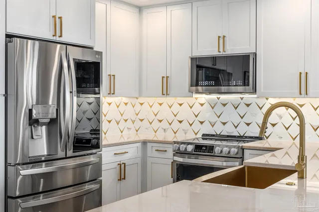 a kitchen with stainless steel appliances granite countertop a sink a stove a refrigerator and a oven with wooden floor