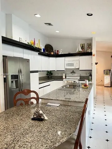 a kitchen with sink a counter and chairs