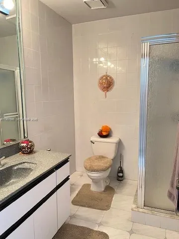 a bathroom with a granite countertop sink a toilet a mirror and shower