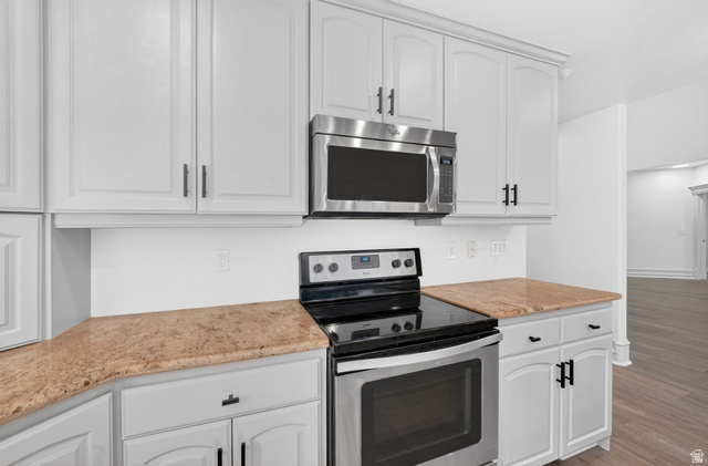 883 East 700 South Springville, UT 84663 - Photo 14 of 59 Kitchen featuring white cabinetry with dark hardware, a stainless steel microwave, a stainless steel and black electric range, and light-toned countertops