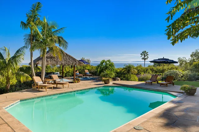 a view of a swimming pool with lawn chairs under an umbrella