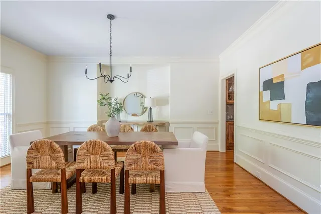 a dining room with wooden floor a chandelier a glass table and chairs