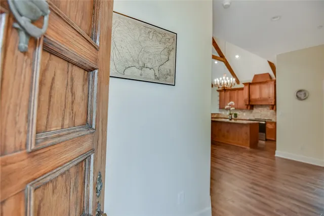 a view of a hallway with wooden floor and a kitchen