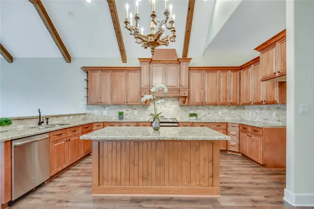 a kitchen with stainless steel appliances granite countertop a sink dishwasher stove and wooden cabinets with wooden floor