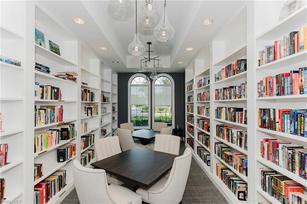6441 Liberty Street Ave Maria, FL 34142 - Photo 41 of 48 a living room with lots of books dining table a rug and a book shelf