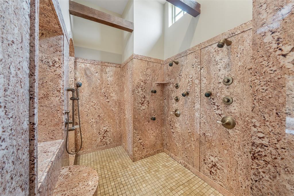 20389 County Road 178 Flint, TX 75762 - Photo 28 of 40 Walk-in shower featuring extensive stone-finish walls, a built-in stone bench, multiple body sprayers, a handheld shower fixture, and a gridded tile floor