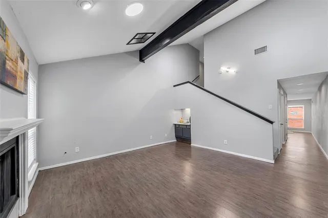 a view of an empty room with a window and wooden floor
