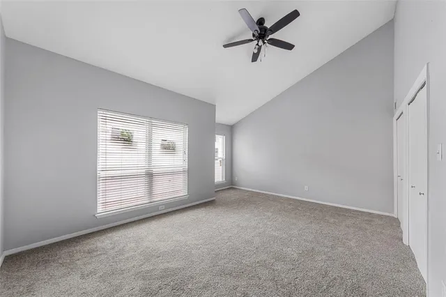 an empty room with windows and ceiling fan