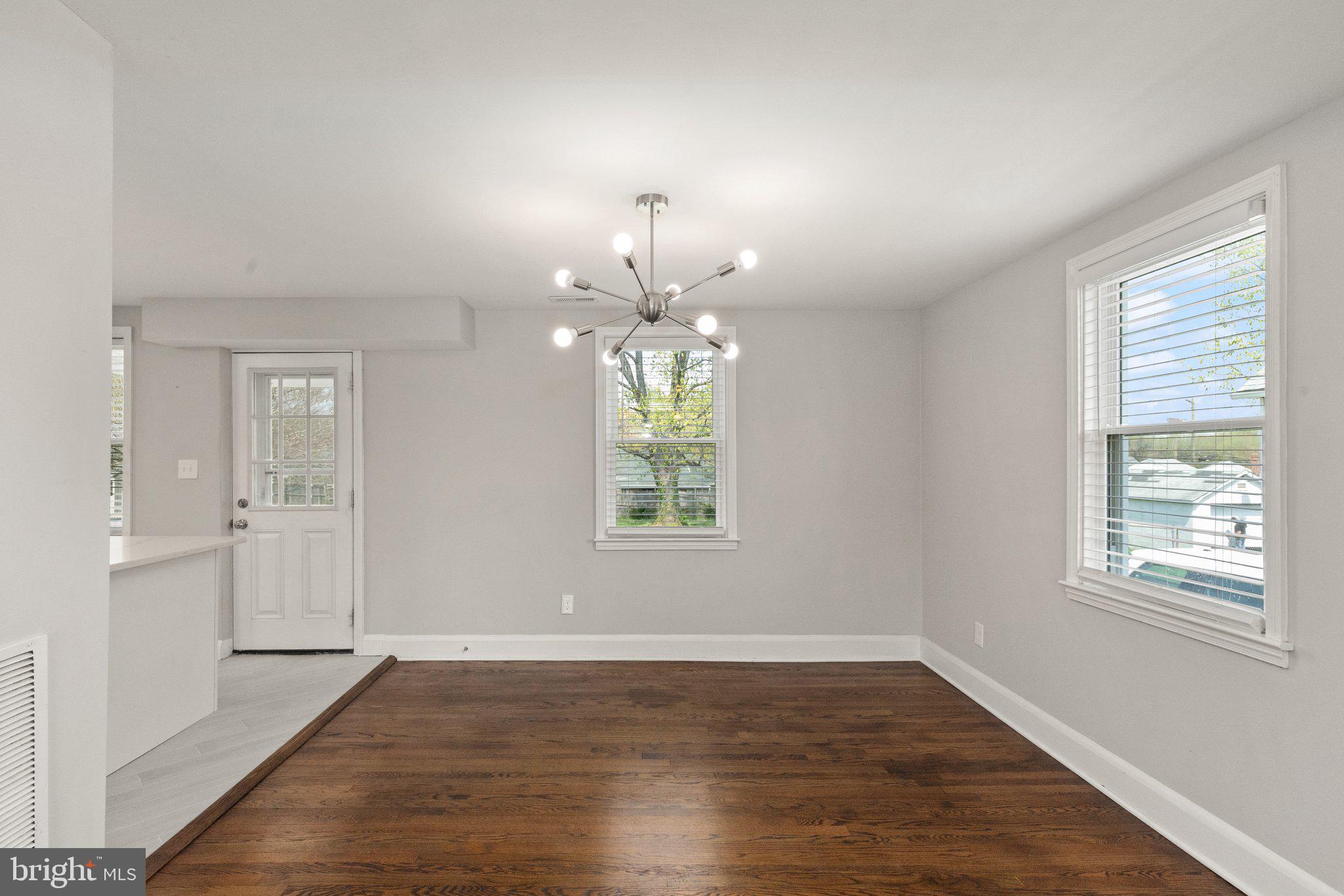 7512 Brightside Avenue Baltimore, MD 21237 - Photo 11 of 32 an empty room with wooden floor chandelier and windows