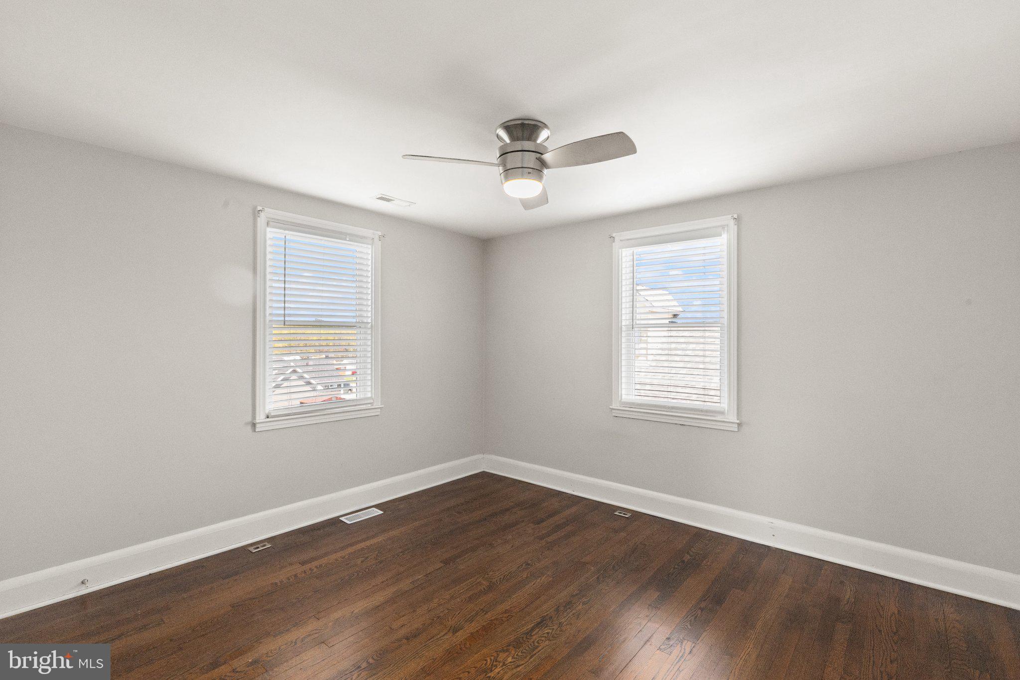 7512 Brightside Avenue Baltimore, MD 21237 - Photo 14 of 32 an empty room with wooden floor ceiling fan and windows