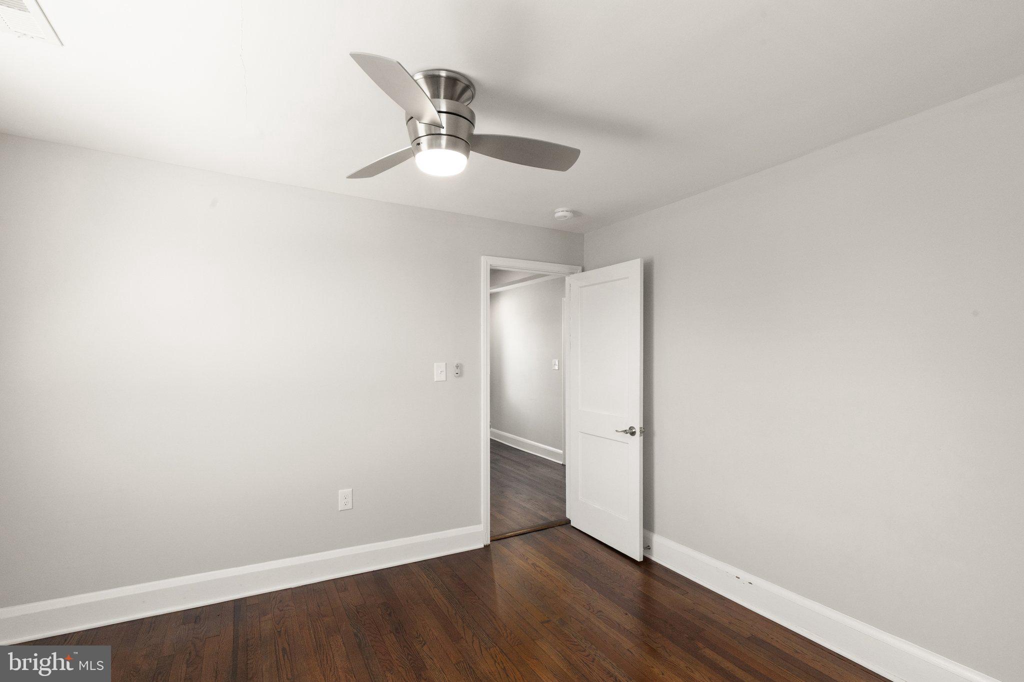 7512 Brightside Avenue Baltimore, MD 21237 - Photo 17 of 32 an empty room with wooden floor fan and windows