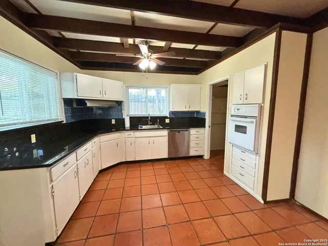 a white kitchen with a sink a counter top space stainless steel appliances and cabinets