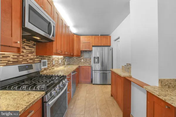 a kitchen with granite countertop a refrigerator stove top oven and sink