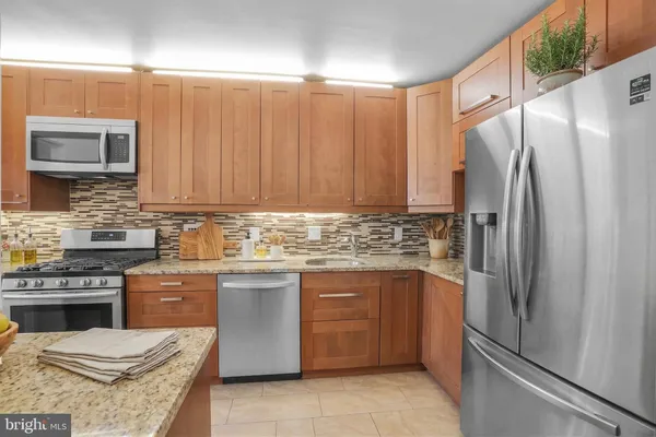 a kitchen with stainless steel appliances granite countertop a refrigerator and a stove top oven