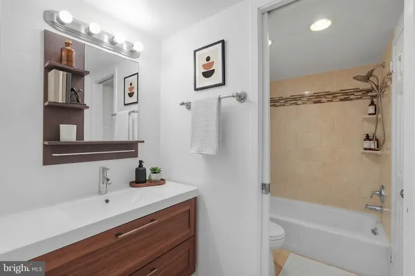 a bathroom with a bathtub shower sink vanity and mirror