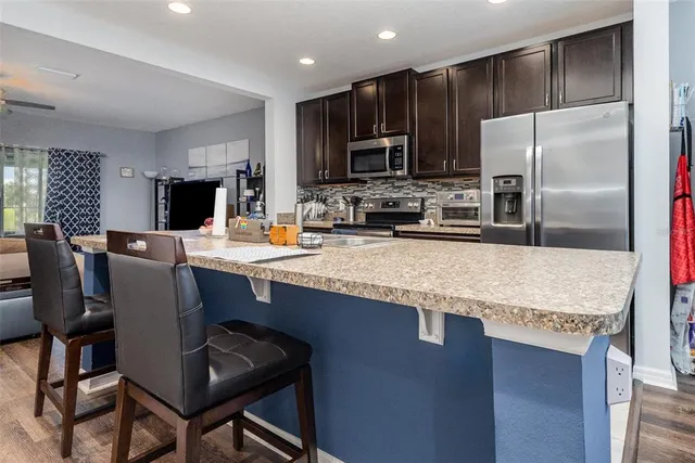 a kitchen with stainless steel appliances granite countertop a stove microwave refrigerator and sink