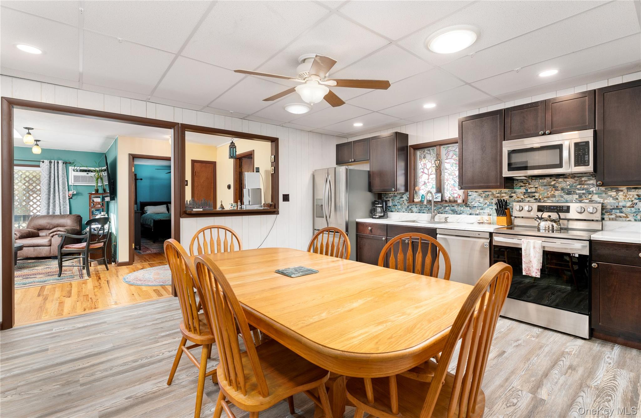 16 Daisy Place Selden, NY 11784 - Photo 8 of 19 a kitchen with stainless steel appliances kitchen island granite countertop a dining table chairs refrigerator and microwave