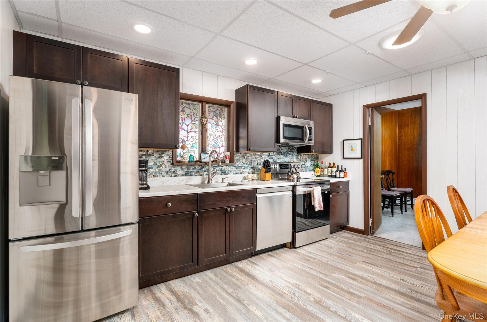 16 Daisy Place Selden, NY 11784 - Photo 9 of 19 a kitchen with stainless steel appliances granite countertop a refrigerator a stove top oven a sink dishwasher and white cabinets with wooden floor