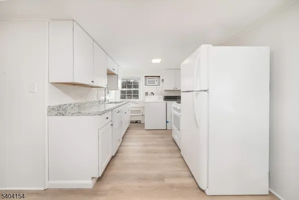 a kitchen with white cabinets and white appliances